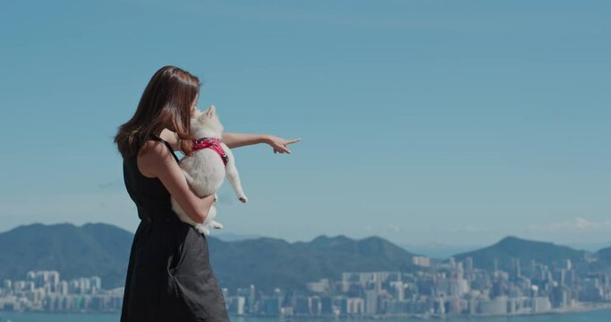 Woman hug with her dog and look at the city from top
