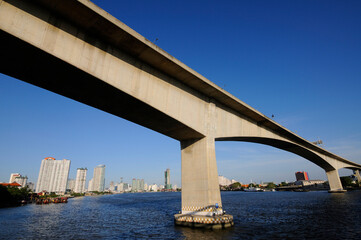 concrete bridge across the river in the city with blue sky