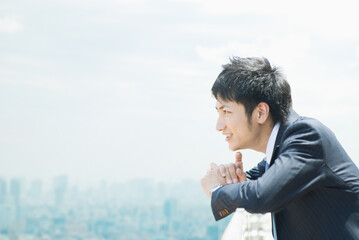 ビルの屋上で遠くを見るビジネスマン