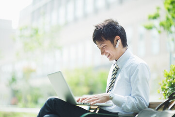 屋外でノートパソコンを操作するビジネスマン