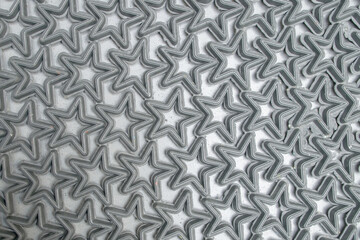 A fragment of a doormat consisting of raised contours of rubber black stars fused into a single structured pattern, lying on a gray concrete floor. Modern geometric synthetic abstract background.