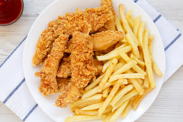Homemade Crispy Chicken Tenders and French Fries on a white plate, top view. Flat  lay, overhead, from above.