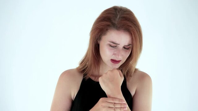Young pretty woman suffers from hand or wrist pain. She holding her acute pain in hand, Studio shot isolated on white background. Carpal tunnel syndrome, arthritis, neurological disease concept.
