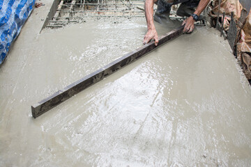 Leveling concrete with trowels, laborer spreading poured concrete