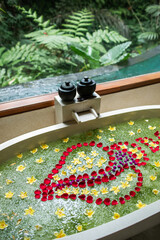 Luxury stone bath tub with tropical flowers for beauty spa treatment, relaxation in hotel. Jungle window view. Bali style.