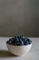 Fresh blueberry in ivory bowl on dark grey background. Freshness of sweet ripe berries