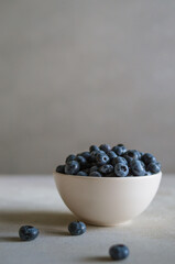 Fresh blueberry in ivory bowl on dark grey background. Freshness of sweet ripe berries