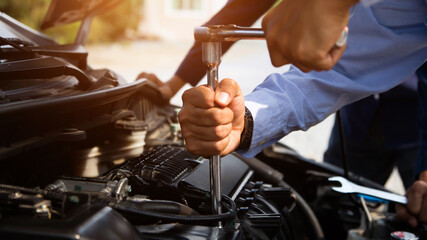 Auto mechanic hands using wrench to repair a car engine. concepts of car care fix repair service and insurance.