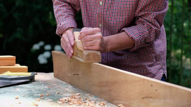 Craftswoman working with carpentry plane outdoors. Close-up view. Woodworking concept.