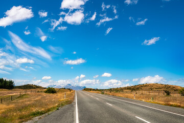 Fototapeta premium Mount Cook State Highway in New Zealand's South Island is one of the most picturesque alpine roads in the world. Roadside perspective with snow capped mountains in the background.