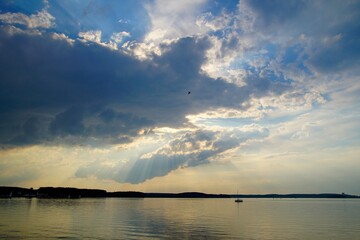 Quiet summer warm evening over the lake. Sun and clouds. Sunset. Horizontal landscape