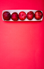 barquette de prunes sur fond rouge