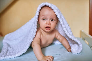 Baby boy 4 months lies on his stomach under a white baby blanket