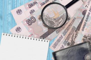 50 russian rubles bills and magnifying glass with black purse and notepad. Concept of counterfeit...