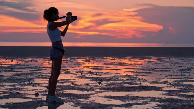 Woman take photo of the sunset along the beach