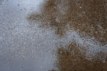 texture of asphalt chips covered with water and circles from raindrops