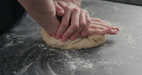 man working with dough on concrete countertop
