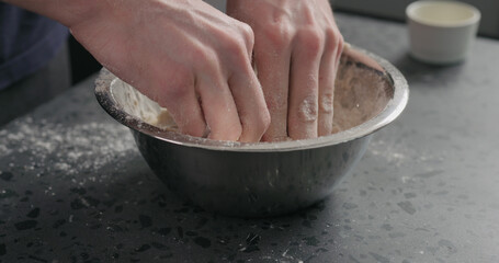 Obraz na płótnie Canvas man mixing dough in steel bowl on concrete countertop