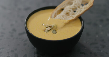 creamy squash soup in black bowl with toasted crouton