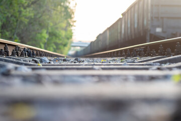 Blurred background with gravel, railroad tracks and standing freight train.