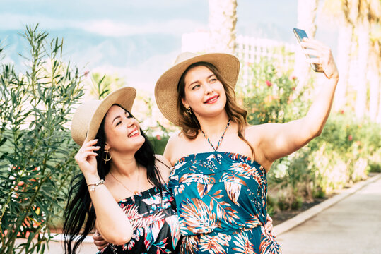 Couple of happy and beautiful curvy health caucasian gilrs enjoying the outdoor leisure activity walking at the park and soing a video call conference connecting with people