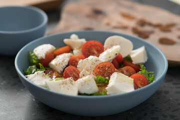 salad with mozzarella, tomatoes and lettuce in blue bowl