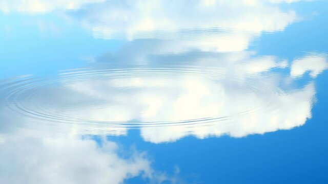 Reflection of blue sky with white clouds in water, circles flowing around water surface. Summer sunny day on nature. Fish splashing in the water making round ripples.