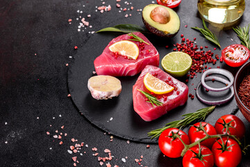 Fresh tuna fillet steaks with spices and herbs on a black background