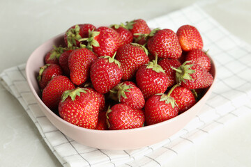 Delicious ripe strawberries in bowl on light grey marble table, closeup
