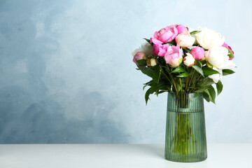 Bouquet of beautiful peonies in vase on white table. Space for text