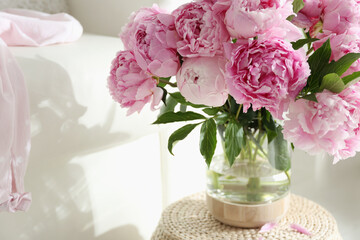 Bouquet of beautiful peonies on pouf indoors. Space for text