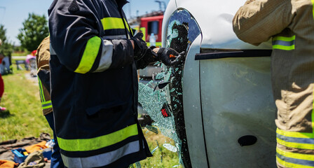 Brave fireman breaking car window and trying to rescue victim of car accident.