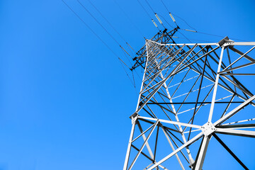 Modern high voltage tower against blue sky, low angle view