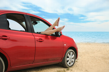 Fototapeta na wymiar Woman showing legs from car, closeup. Summer vacation trip