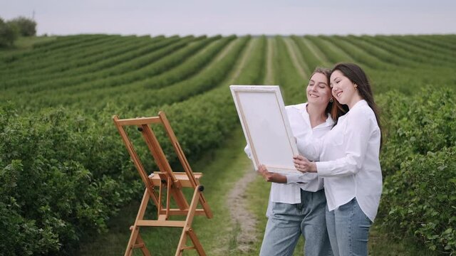 Women in a summer field. Cute lady drawing. Girl in a white shirt.