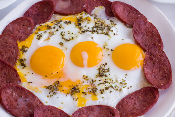 Close up of egg with sausage on white plate.