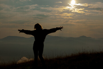silhouette of a girl on a background of clouds sky in the mountains