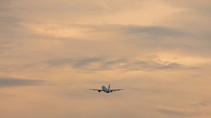 Unique beautiful dramatic gray and white clouds on light blue sky on daylight. The silhouette of airplane rising upward the clouds after takeoff. Air travel concept.