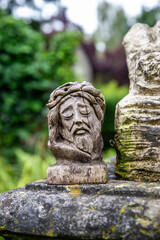 Fototapeta na wymiar Kleine Jesusfigur aus Holz geschnitzt auf einem Grabstein