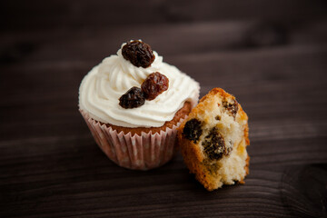 muffin with cream and raisins on a dark wooden background