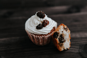 muffin with cream and raisins on a dark wooden background