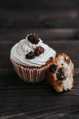 muffin with cream and raisins on a dark wooden background