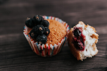 homemade muffin stuffed with black currant, one cracked and dripping. on a dark background
