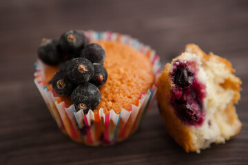 homemade muffin stuffed with black currant, one cracked and dripping. on a dark background