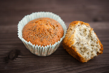 two homemade poppy seed muffins, one broken. on a dark background