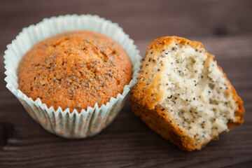 two homemade poppy seed muffins, one broken. on a dark background