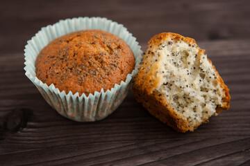 two homemade poppy seed muffins, one broken. on a dark background