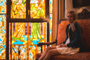 Obraz na płótnie Canvas Young blonde caucasian woman in a white dress and denim jacket enjoying a beautiful medieval hotel in the town of Olite in Navarra. Spain, rural lifestyle. Refreshing on the terrace