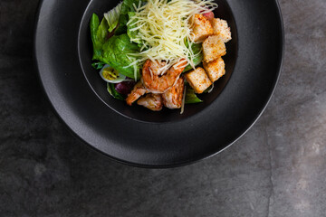 Italian cuisine. Salad with fresh salad greens, shrimp and quail eggs. Dark key photo