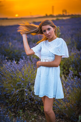 A young blonde Caucasian woman in a white dress in a cultivated lavender field in Navarra, Spain. lifestyle, rural lifestyle in purple lavender flowers at sunset